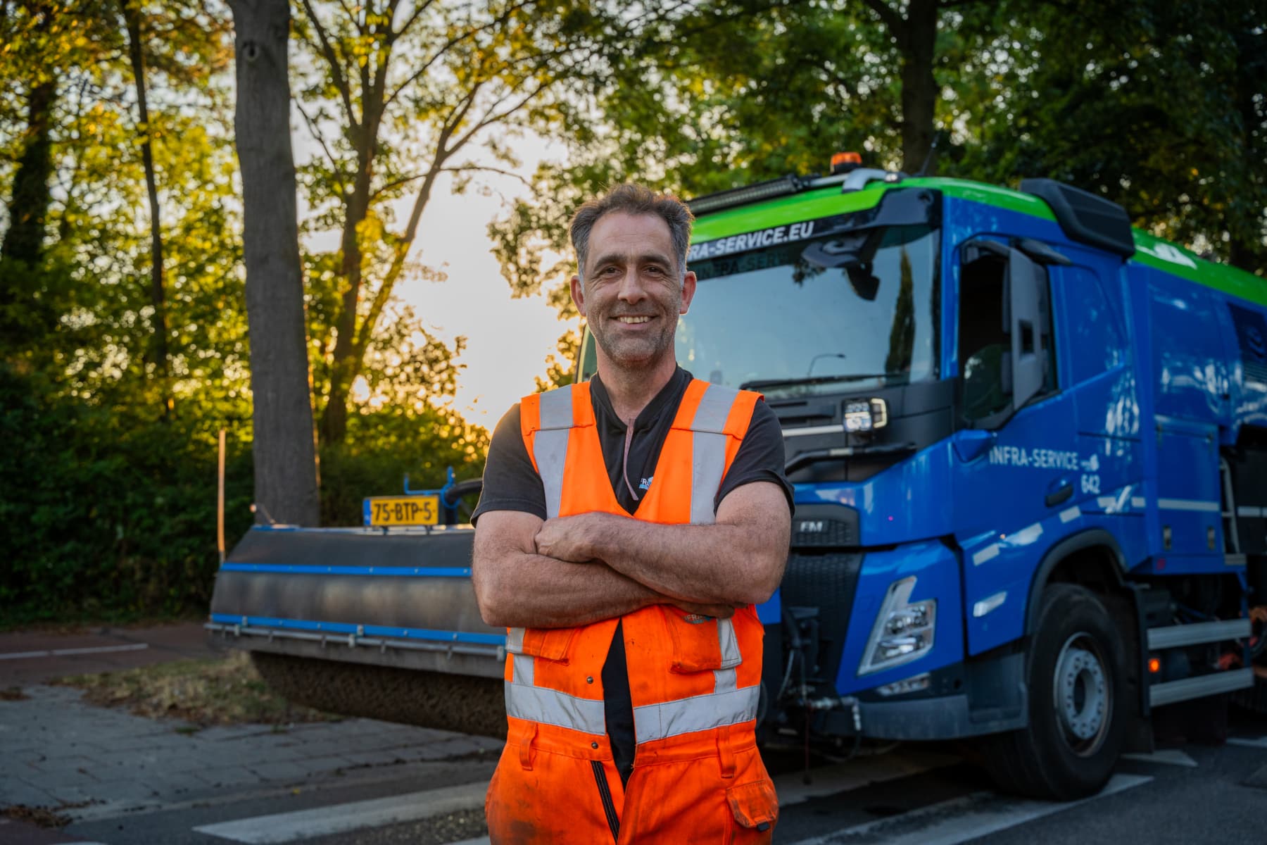 Lachende machinist voor een veegwagen van Infra Service