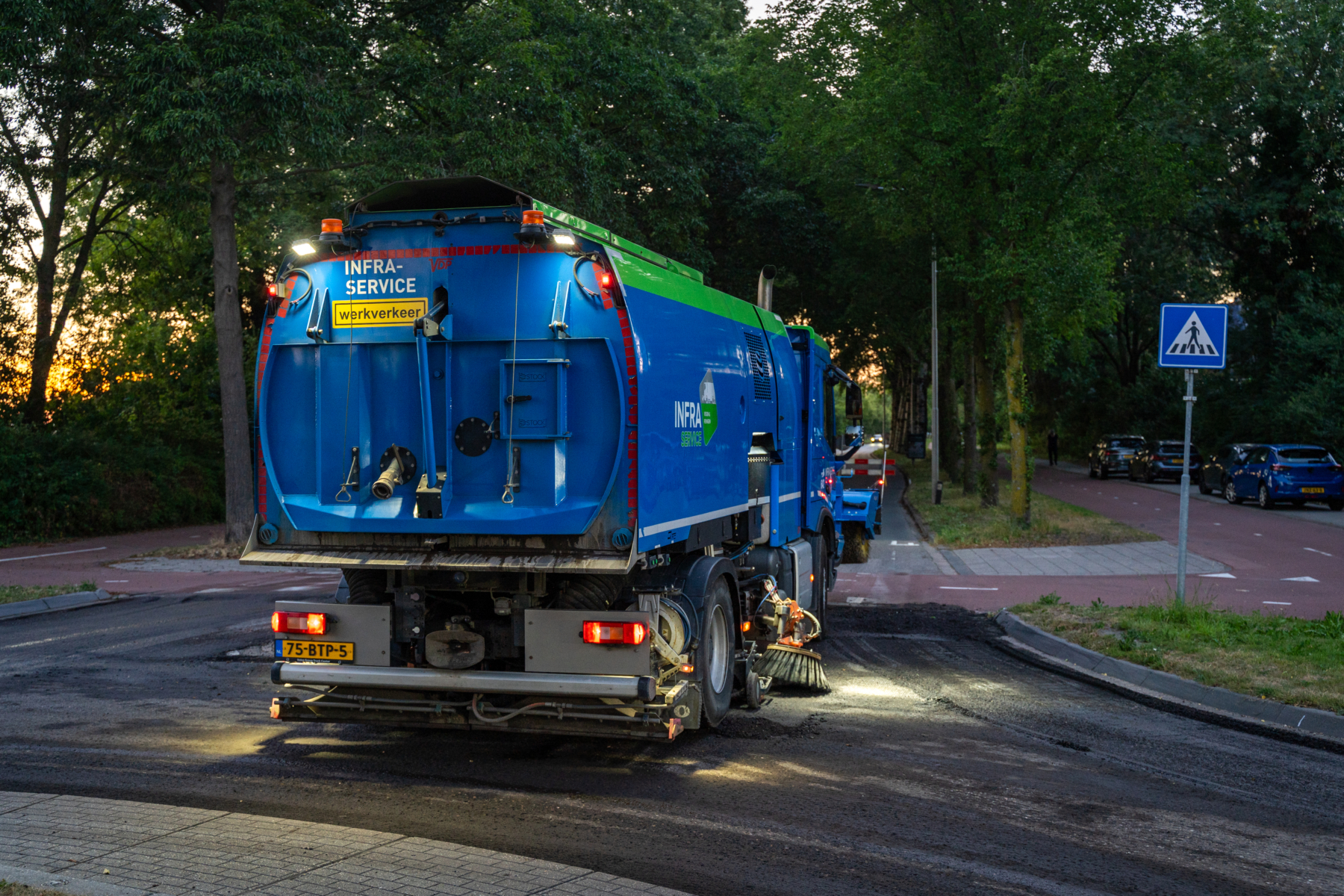Veegwagen rijdt in de avond over een weg