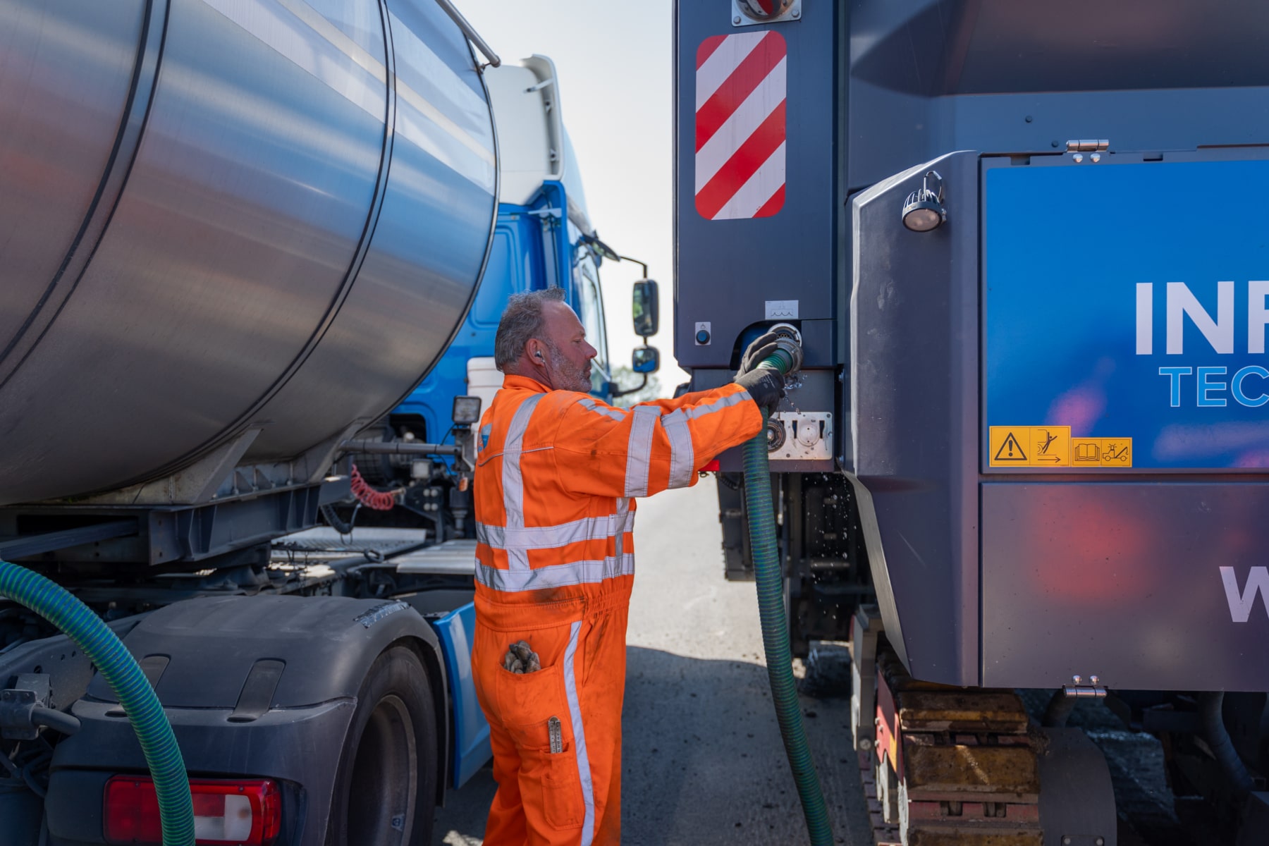 Medewerker vult water bij aan een tankwagen