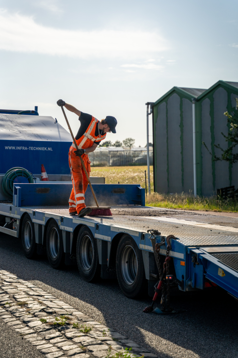 Medewerker veegt de laadvloer van een dieplader schoon